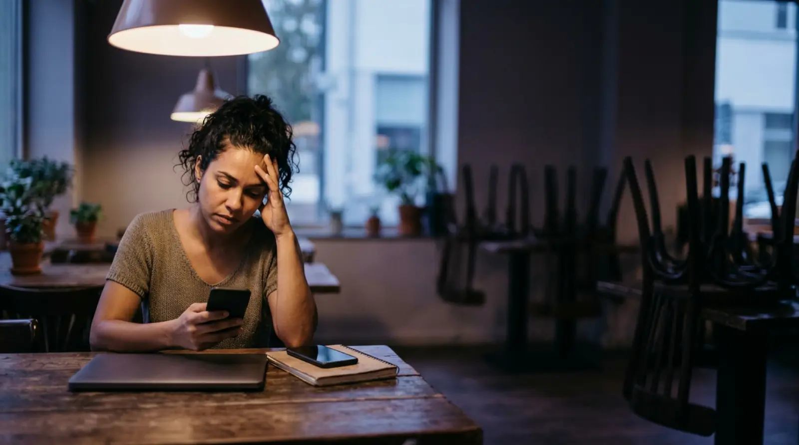 Fim do expediente: alguém olha o celular, cansada, num restaurante já fechado